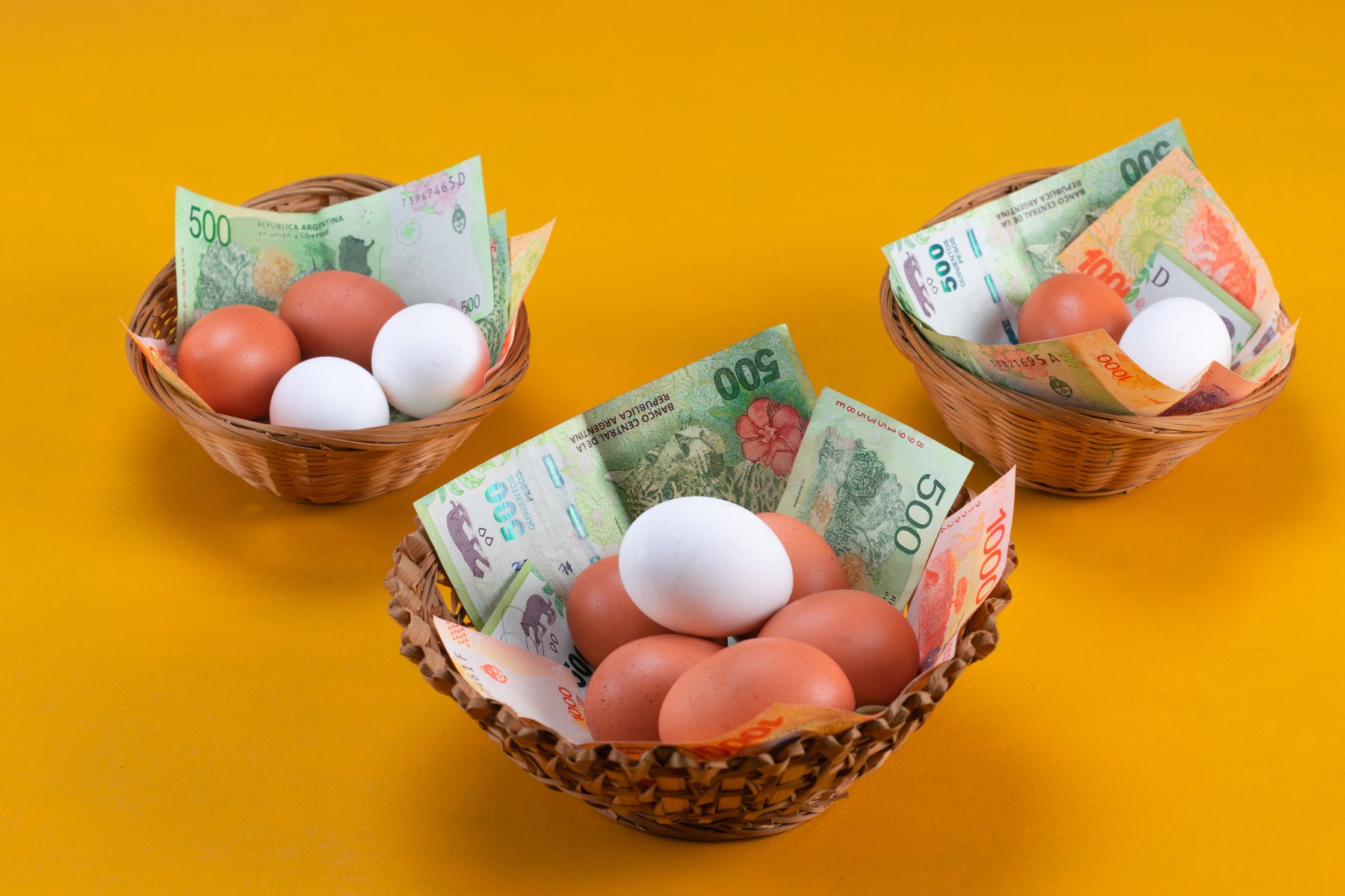 Eggs of different colors on money distributed in different baskets.